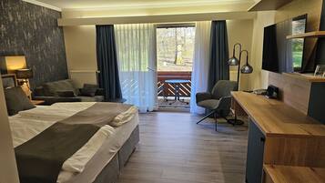 Une chambre d’hôtel comprenant un lit, un bureau, une chaise, une télévision et un balcon avec une table et des chaises.
