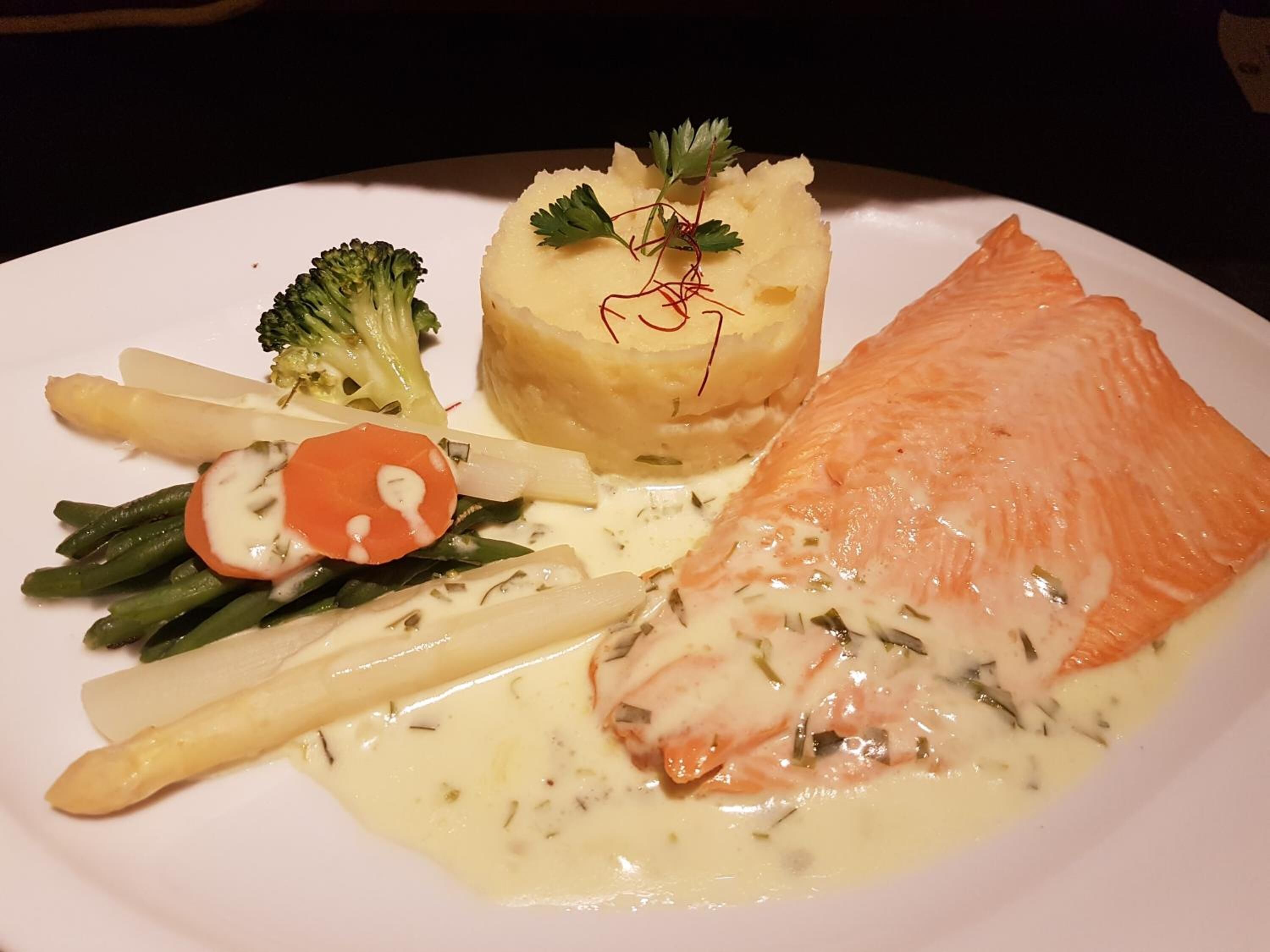 Ein Teller mit Lachs, Kartoffelstampf, Brokkoli, Spargel und einer Karottescheibe.