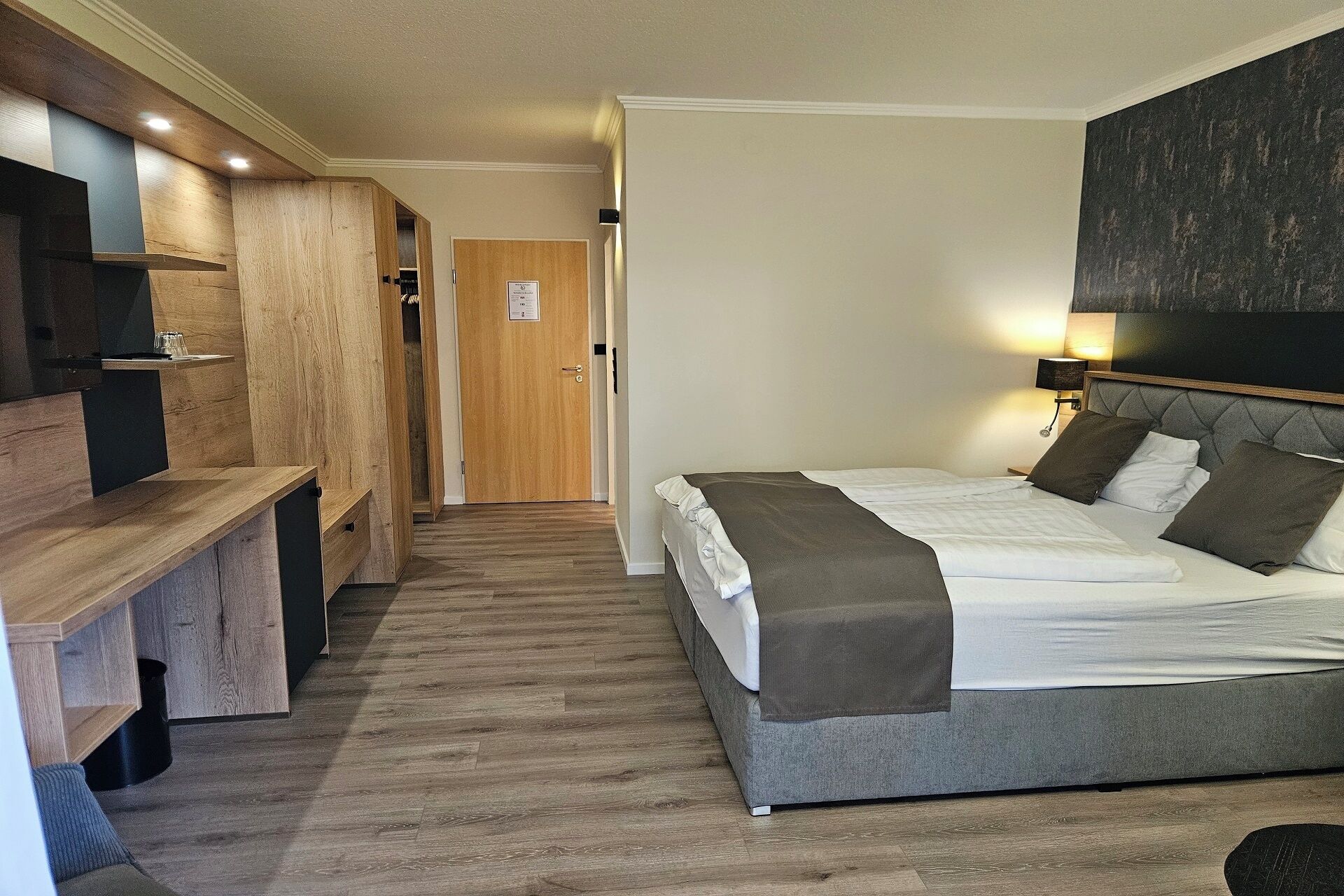 Ein Hotelzimmer mit einem Bett, einem Nachttisch und einem Holzschrank.