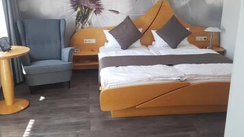 A hotel room with a bed, a chair, a small table, and a wall with a floral mural.