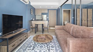 Ein modernes Wohnzimmer mit Fernseher, braunem Ledersofa, rundem Couchtisch und einem Teppich mit Muster.