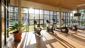 Ein Fitnessraum mit Trainingsgeräten, großen Fenstern und einer Zimmerpflanze.