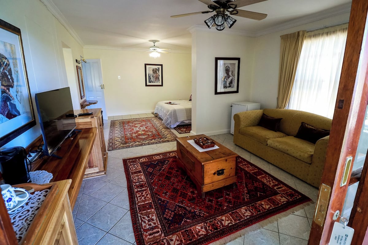 A living room with a TV, wooden bench, sofa, and a ceiling fan.