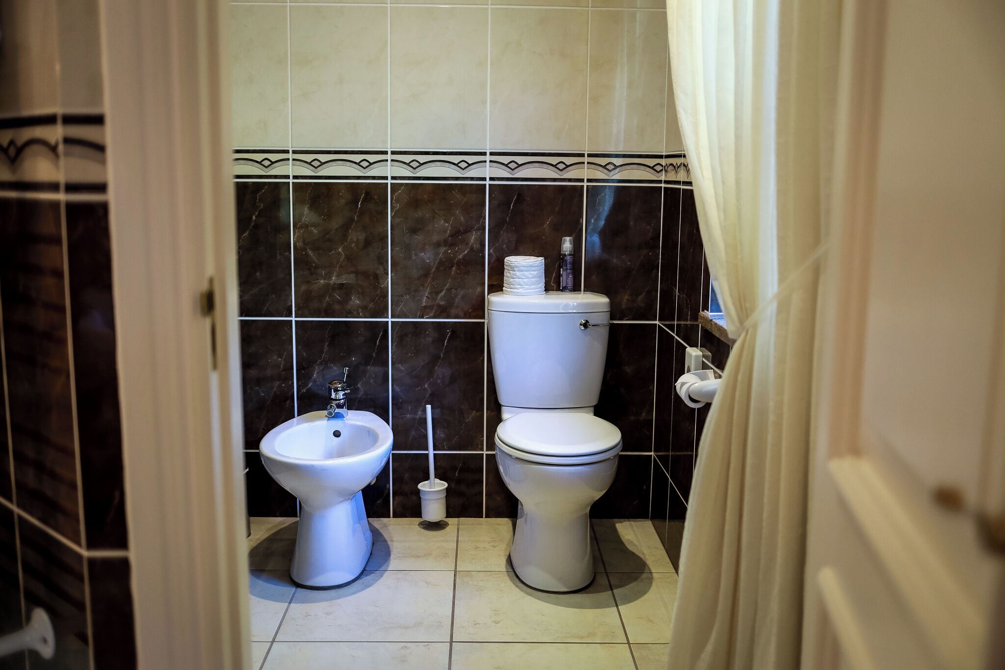 A bathroom with a toilet, bidet, and a towel rack.