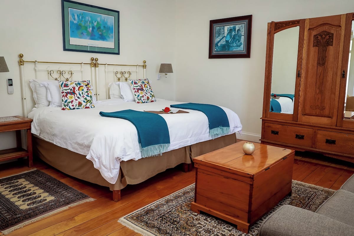 A neatly arranged bedroom with a large bed, two bedside tables, a wooden dresser, and a mirror.