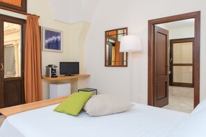 A hotel room with a bed, a desk with a computer, a lamp, and a mirror. - Castromediano Suite Palace (Lecce)