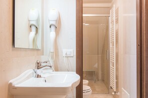 A bathroom with a white sink, a mirror, and two hair dryers mounted on the wall. - Castromediano Suite Palace (Lecce)