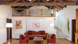 Ein geräumiges Wohnzimmer mit hohen Decken, einer Holztreppe und einem großen Fenster.