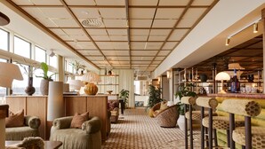 A spacious lobby with a patterned floor, comfortable seating areas, and a bar with stools. - Hjortviken Country Club (Hindas)