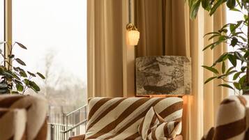 A cozy living room with striped armchairs, a sofa, a decorative lamp, and a view of the outdoors.