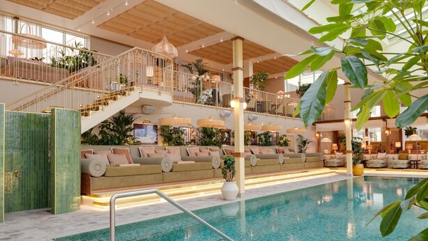A spacious indoor swimming pool with a sunlit atrium, multiple levels with seating, and a variety of plants. - Hjortviken Country Club (Hindas)