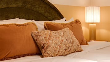 Una cama bien hecha con almohadas marrones y estampadas, un cabecero y dos cuadros en la pared.