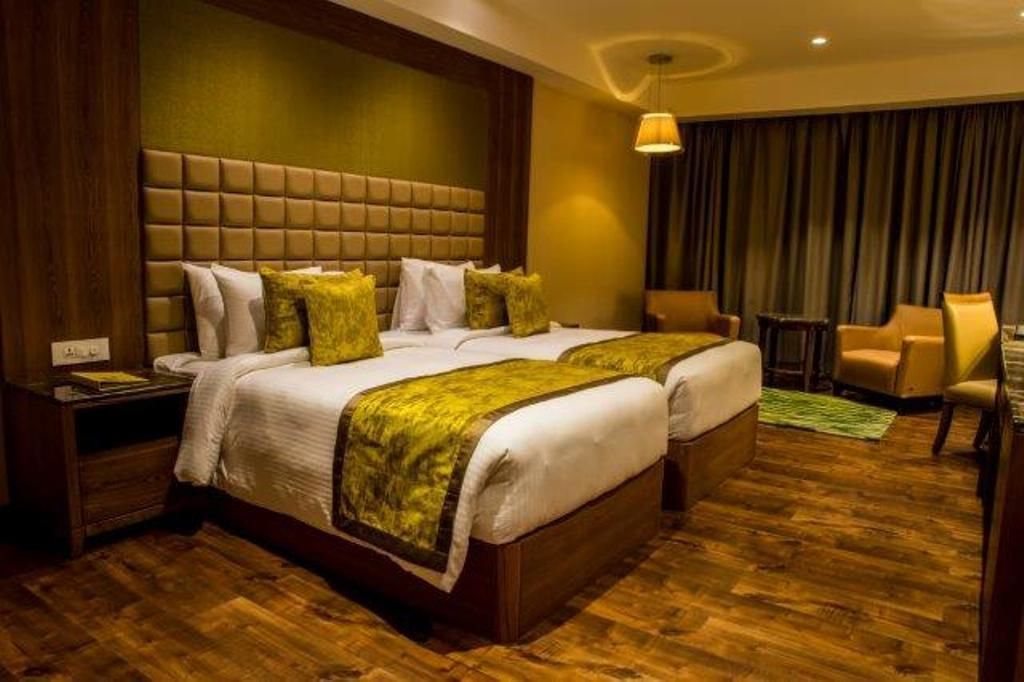 Quarto de hotel com uma cama grande, duas mesas de cabeceira, uma cadeira e um abajur.