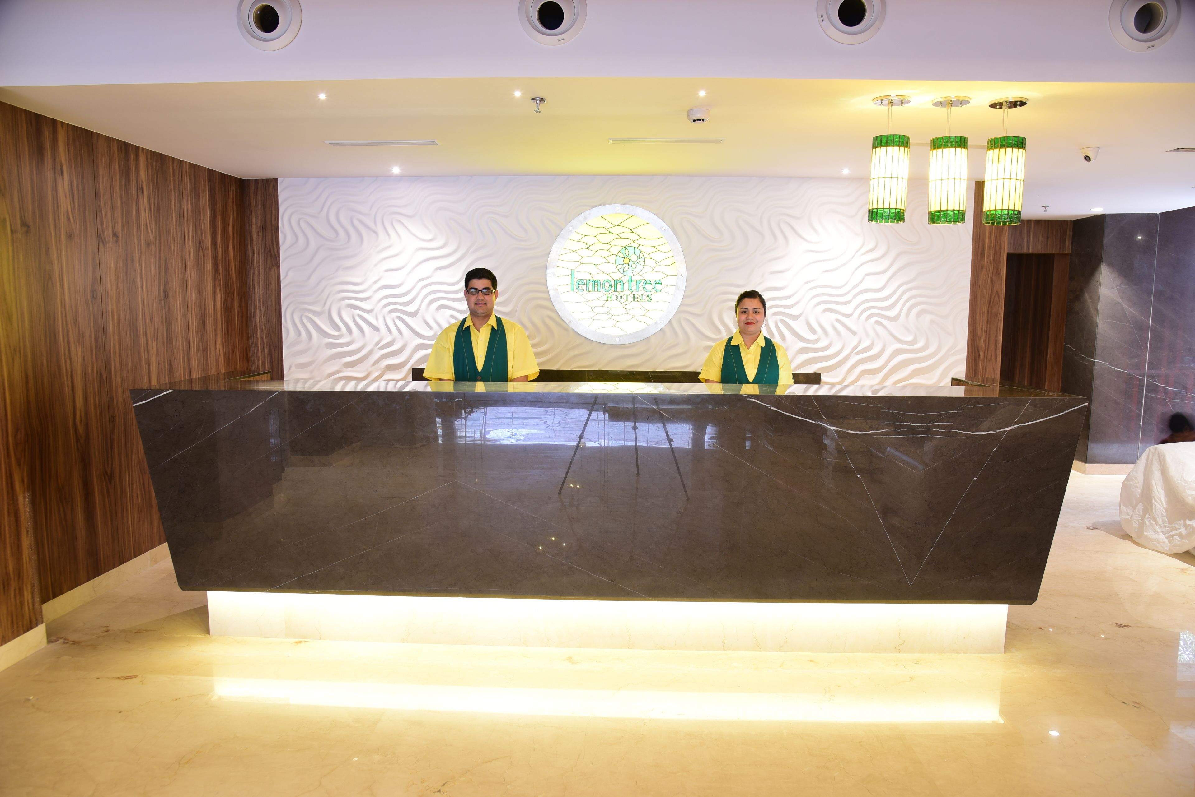 A reception desk with two staff members, a logo, and a modern interior design.