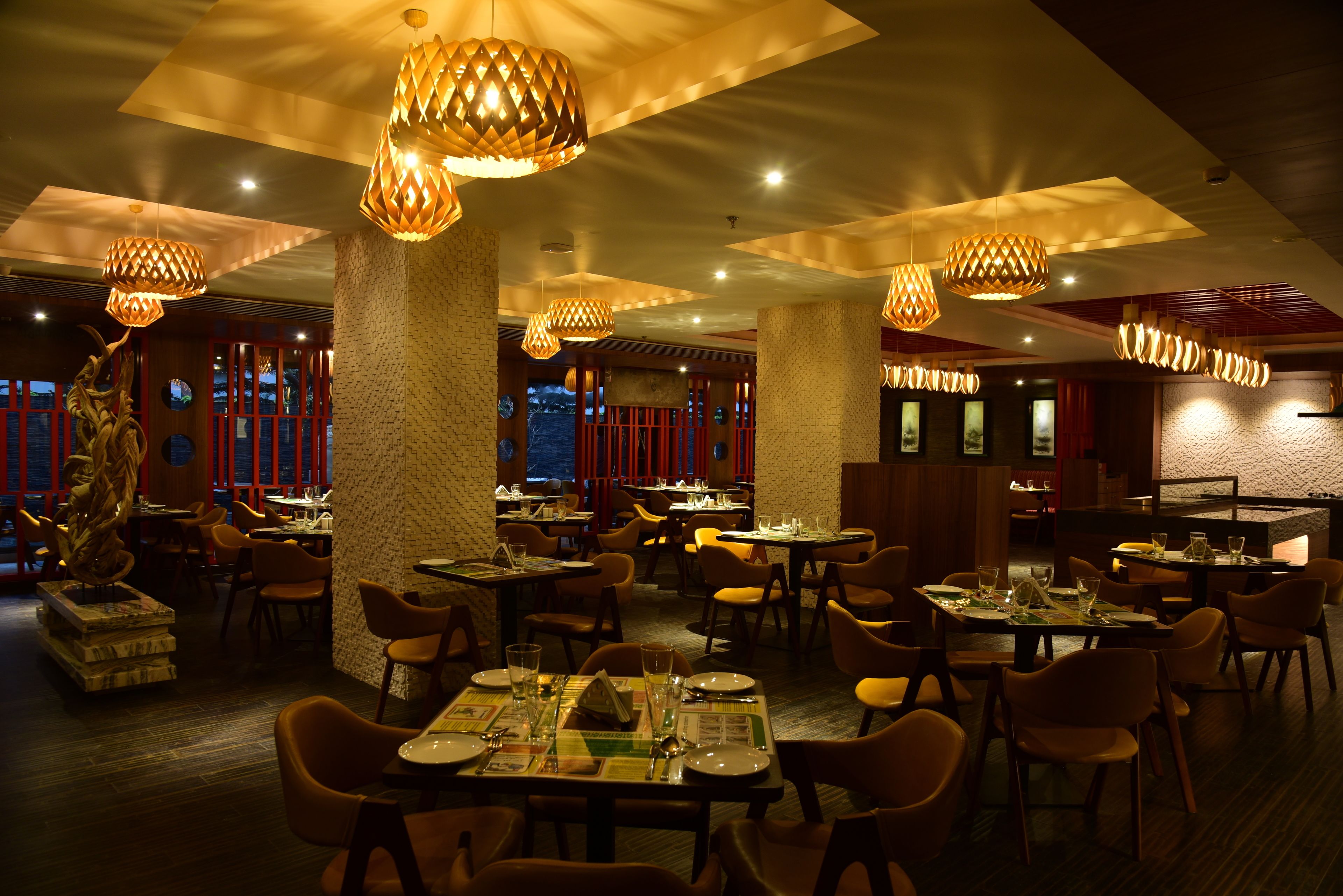 A restaurant with multiple tables and chairs, warm lighting, and decorative elements.