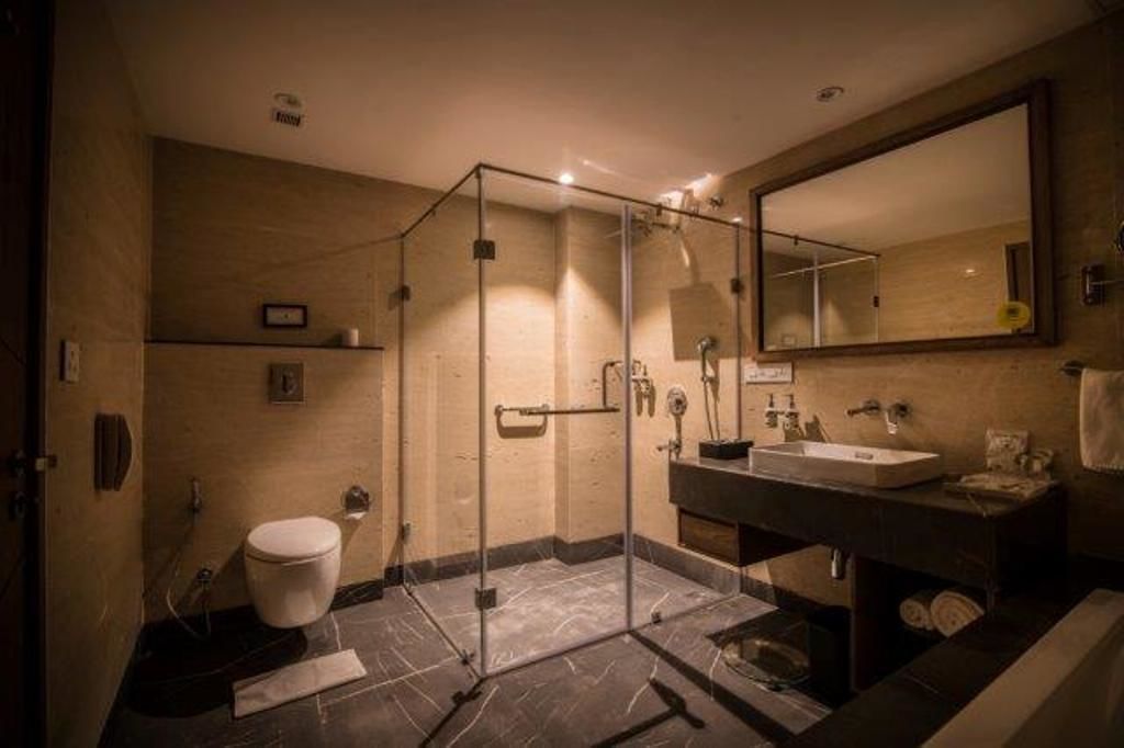 A modern bathroom with a glass-enclosed shower, a toilet, and a sink with a mirror above.