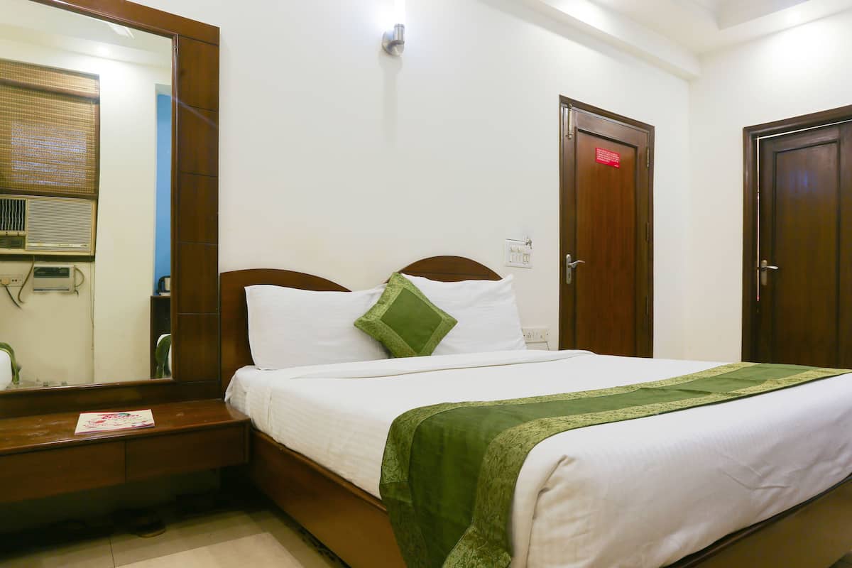 A neatly made bed with white and green linens, a wooden headboard, and a bedside table with a lamp.
