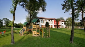 A playground with wooden structures and a building in the background.