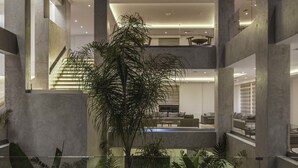 Ein mehrgeschossiges Interieur mit einer zentralen Treppe, einem Poolbereich und verschiedenen Zimmerpflanzen.