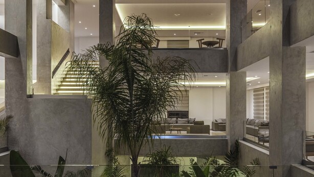 Un interior de varios niveles con una escalera central, una zona de piscina y una variedad de plantas de interior.