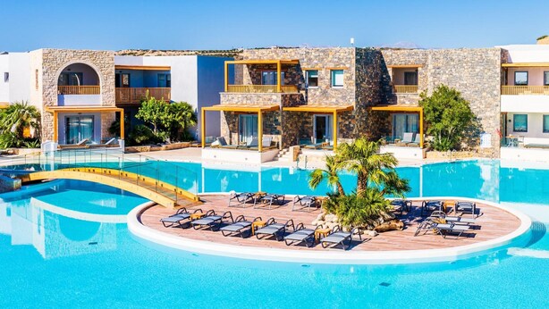 Ein Resort mit großem Pool, mehreren Balkonen und einer Holzterrasse mit Liegestühlen.