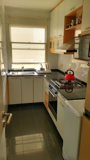 A compact kitchen with a gas stove, oven, and a microwave. - Palermo Open View (Buenos Aires)