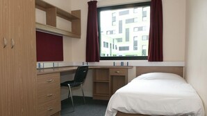 Una camera piccola con un letto, una scrivania, una sedia e un armadio.