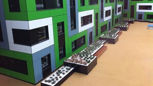 Un edificio moderno dal design modulare, con numerose finestre e tocchi di colore verde e bianco.