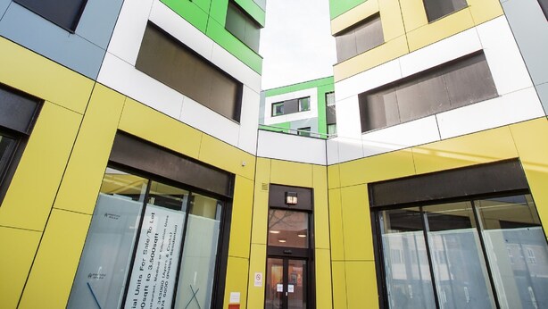 Un edificio moderno con una facciata geometrica particolare, caratterizzata da pannelli colorati e ampie finestre.