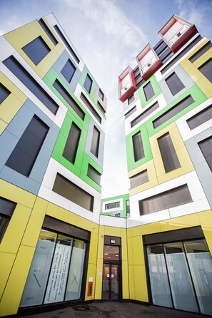 A modern building with a unique geometric facade, featuring multiple colored panels and large windows. - University of Essex - Southend Campus  (Southend-on-Sea)