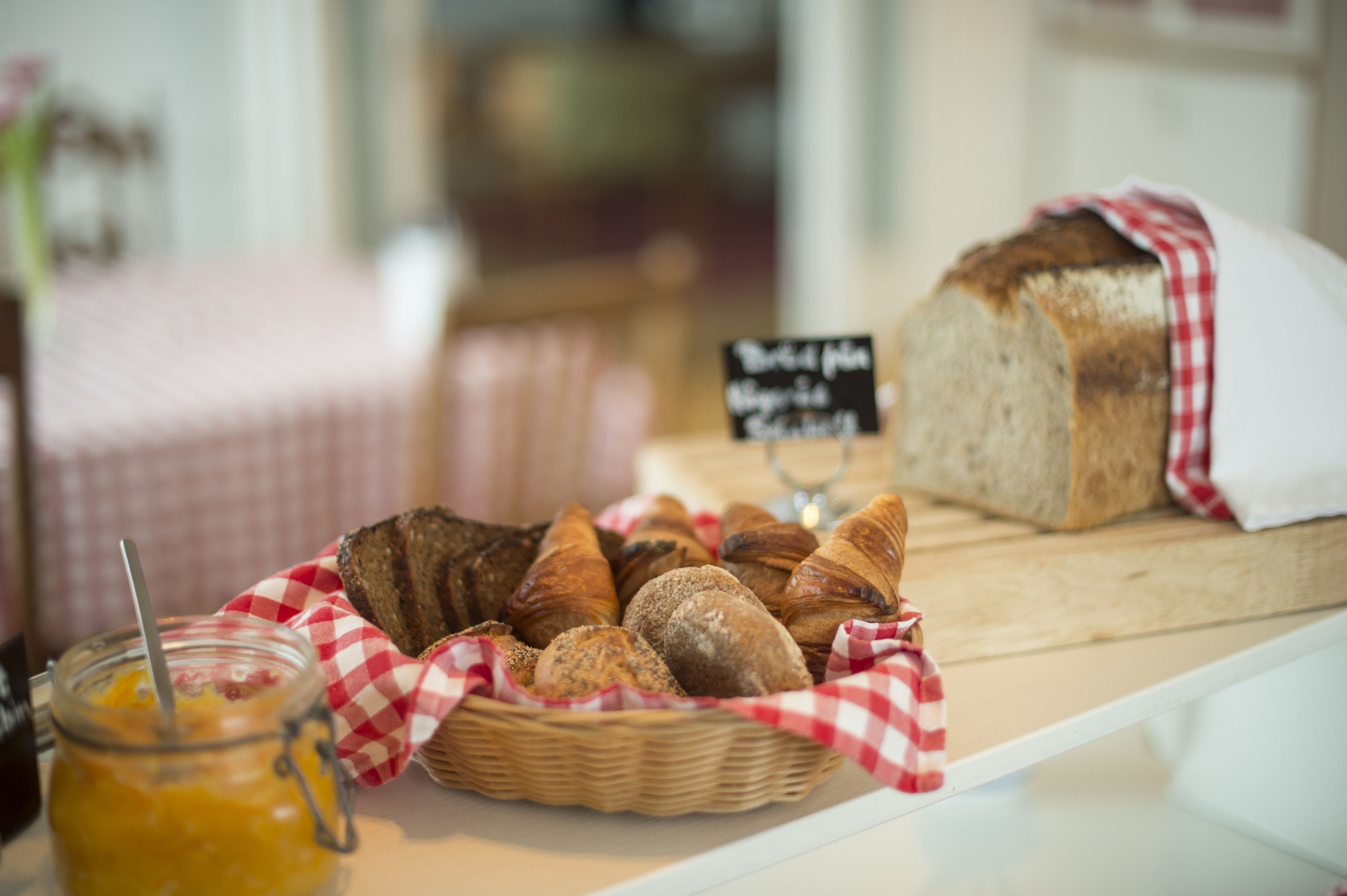 A variety of breads and pastries displayed on a table with a checkered cloth.