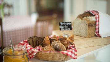 A variety of breads and pastries displayed on a table with a checkered cloth.