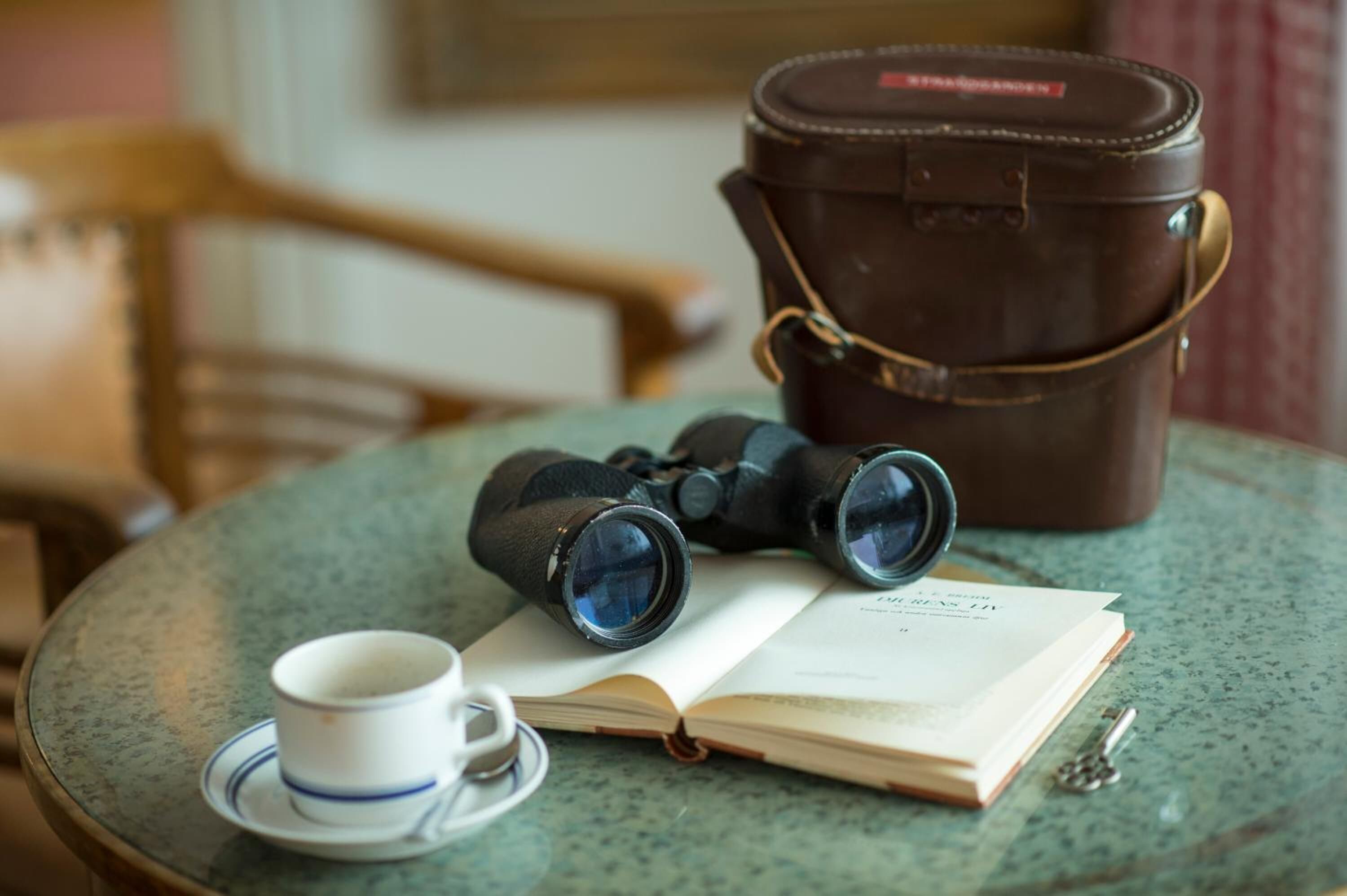 Une table avec des jumelles, un livre, une tasse et une clé.