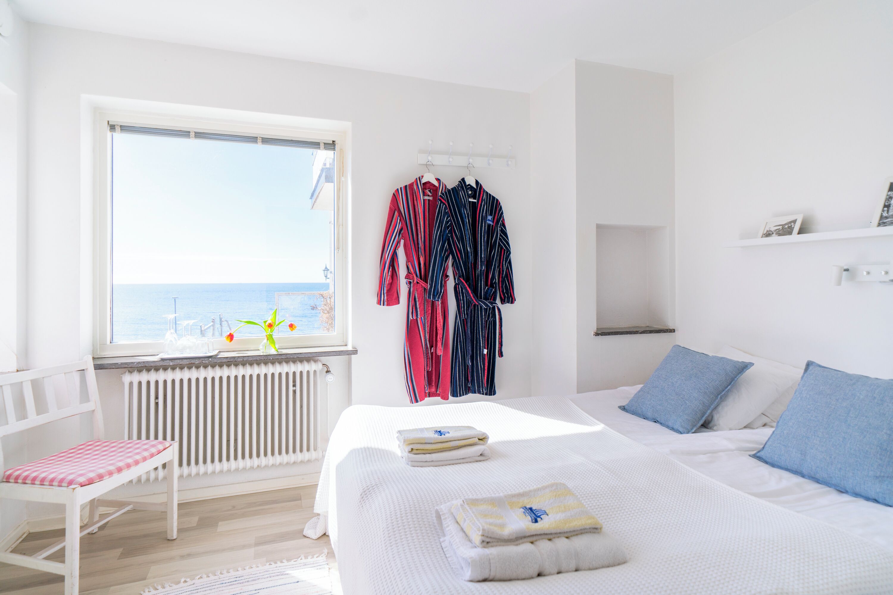 A bedroom with a bed, a chair, a window with a view, and a radiator.