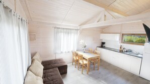 A modern kitchen with wooden cabinets, a dining table, and a sofa. - Duet Domki (Postomino)
