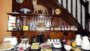 A kitchen with wooden shelves stocked with food items, a cat on the shelf, and various kitchen appliances.