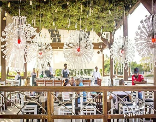 Un espace de restauration en plein air avec des tables et des chaises en bois rustique, entouré de luminaires suspendus.