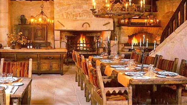 A traditional inn with a long communal dining table, a fireplace, and a staircase leading to an upper level. - Auberge de L'Abbatiale (Auberive)