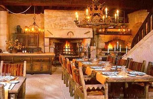 Una posada tradicional con una larga mesa de comedor compartida, una chimenea y una escalera que lleva a un nivel superior.