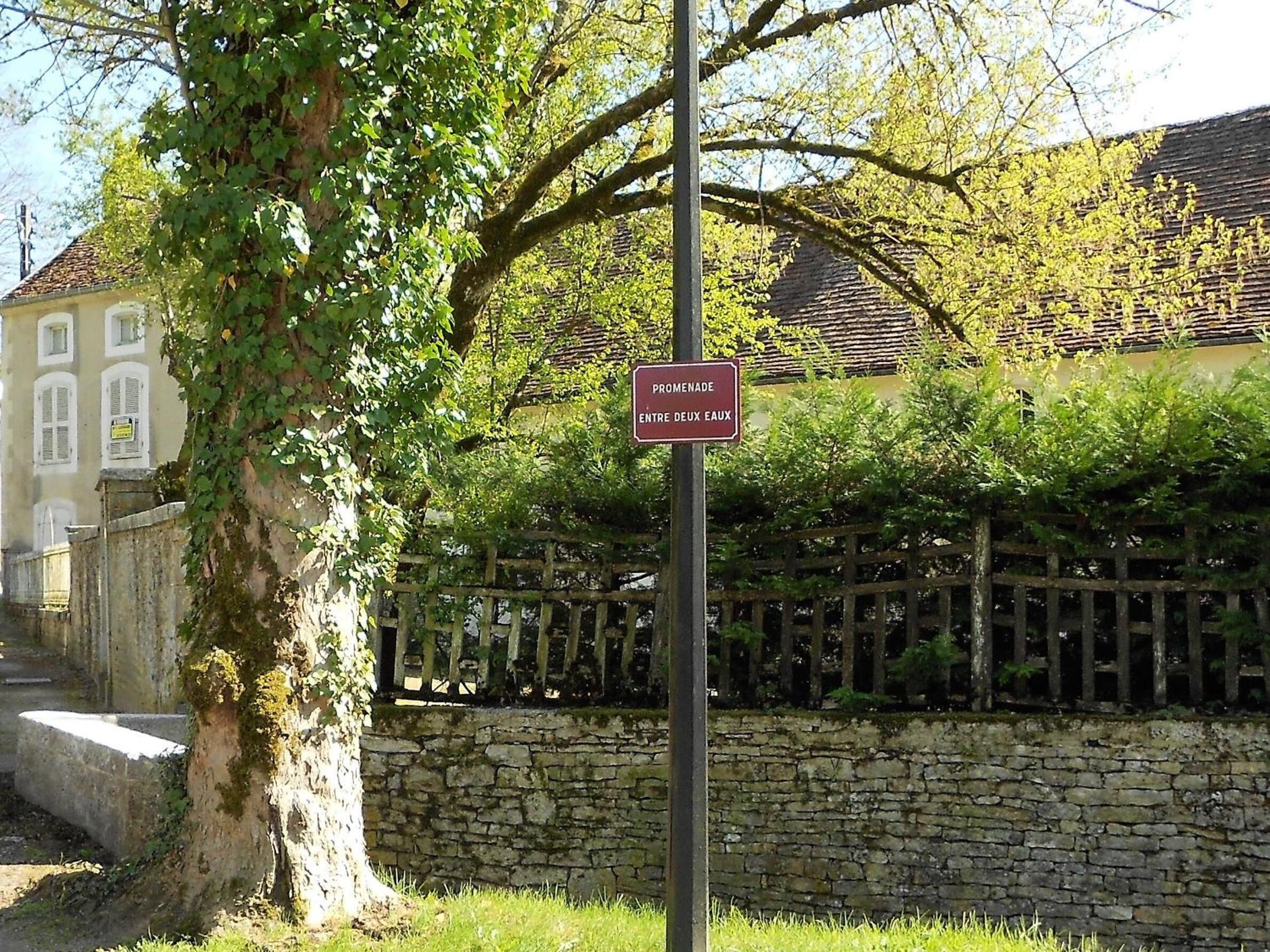 A stone wall with a sign that reads "Promenade Entre Deux Eaux".