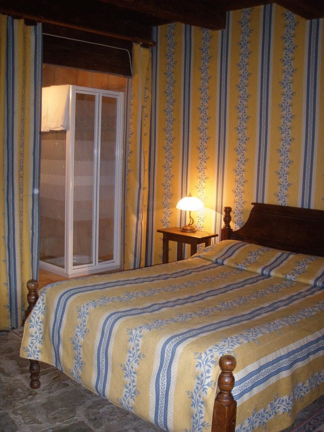 Une chambre à coucher avec un lit, une table de chevet, une lampe et une porte-fenêtre coulissante.