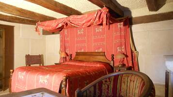 A traditional bedroom with a wooden bed, a chair, and a table with a book.