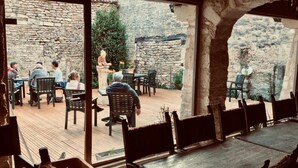 An outdoor dining area with stone walls and wooden furniture. - Auberge de L'Abbatiale (Auberive)
