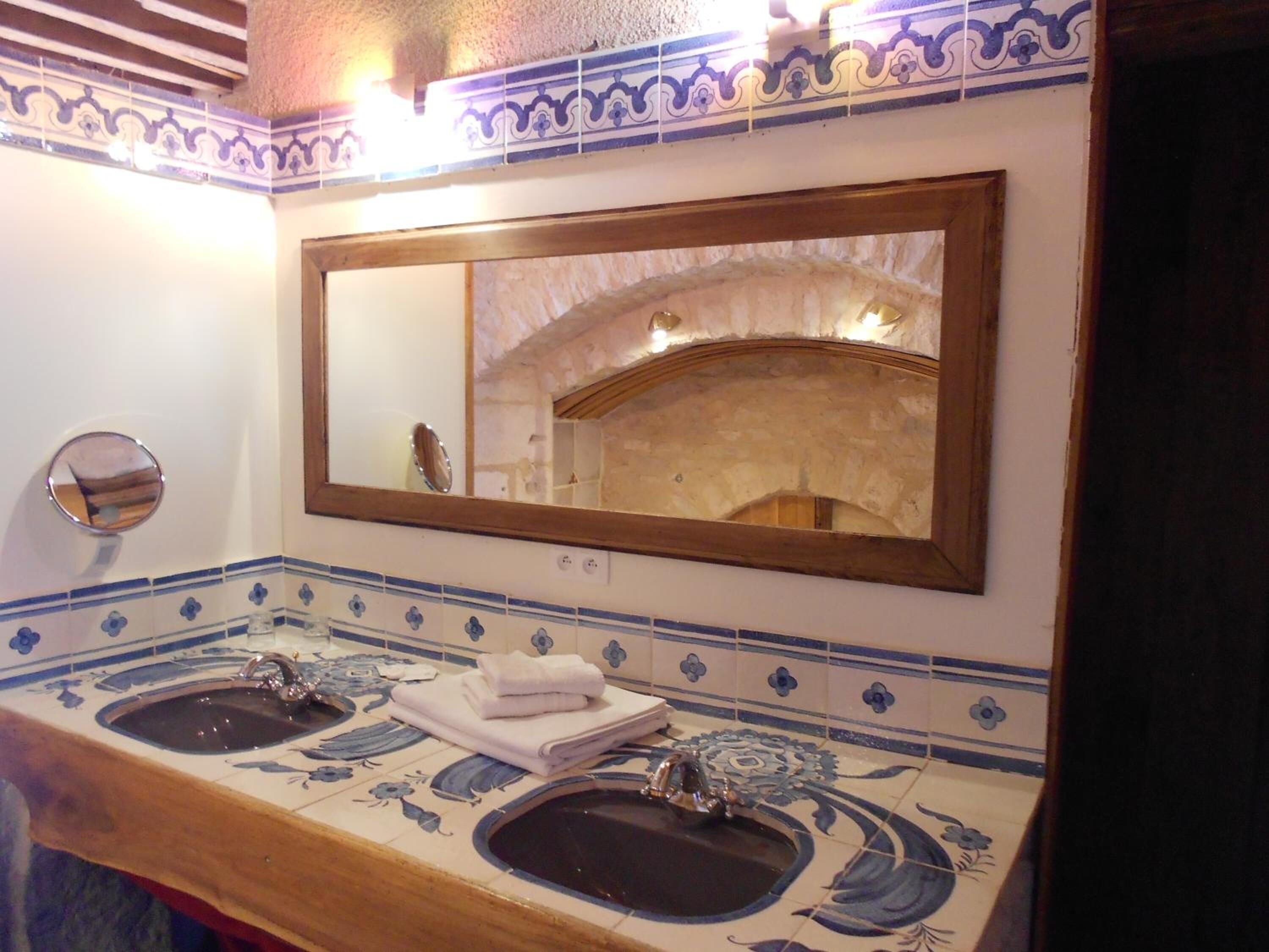 A bathroom with two sinks, a mirror, and decorative tiles.