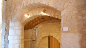 A stone-walled bathroom with a wooden arch, a shower, and a bench. - Auberge de L'Abbatiale (Auberive)