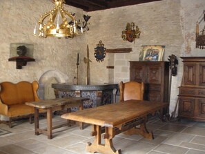 Una habitación rústica con una mesa de madera, sillas de cuero, un candelabro y una pared de piedra.