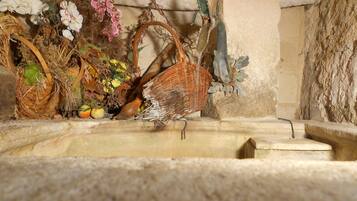 A rustic interior with a stone wall, a woven basket, and a small fountain.