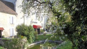 A building with a sign that reads "Villas de la Muerte" in a lush garden setting with a pond. - Auberge de L'Abbatiale (Auberive)