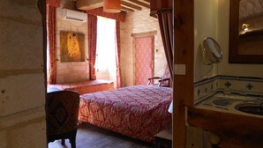 A room with a bed, a chair, a wooden ceiling, a window with curtains, and a tiled sink. - Auberge de L'Abbatiale (Auberive)