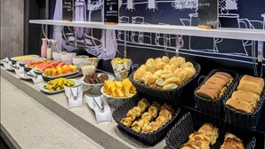A buffet with various food items including fruits, pastries, and bread.